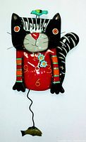 Front view of the colorful handpainted cat pendulum clock with the bird on the head and visible clock face.