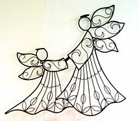 Black metal large angel wall art showing two angels holding hands, decorated with leaf and swirl designs.