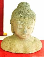 Large grey stone Buddha head sculpture showing textured surface and damaged nose.