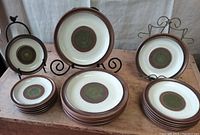 General view of all plates displayed with stands, showing green, brown, and cream potter's wheel design.