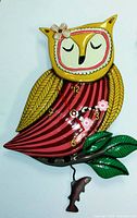 Front view of the hand-painted owl wall clock, showing the owl with closed eyes, yellow head, striped body, and flower accents on the clock hands and owl's head.