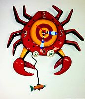 Full view of the crab-shaped pendulum clock with fish pendulum hanging, showing colorful, hand-painted details on the clock face and crab body.