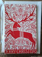 Photo of front of card featuring red stylized Legendary Stag with floral and nature motifs and 'Merry Christmas' text