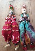 Two large vintage Rajasthani puppets lying flat, showing full length and detailed fabric costumes with painted wooden parts.