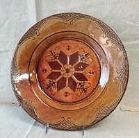 Front view of ceramic plate displaying central geometric floral design and patterned border