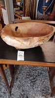 Side view of the large burled wood bowl showing natural wood grain and hole.