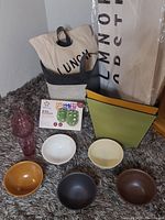 Full lot arrangement showing ceramic bowls, green box, and fabric bags on carpet.