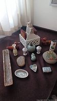 Photo of collection including wood ducks, onyx bud vase, wooden caddy with cards, glass stone owls, small salt and pepper shakers, ceramic trays and decorative items on a dark fabric surface