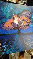 Full view of original painting of girl and boy on clouds with city below and starry sky