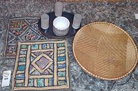 Lot showing woven basket, two stitch art pillow cases, candle holders on tray, and planter pot on carpet.