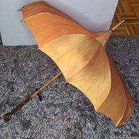 Side view of the open orange pagoda umbrella showing the pleated, scalloped canopy and lucite ring handle base.