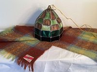 Chandelier and mohair throw blanket shown on a white surface with blanket spread beneath chandelier.