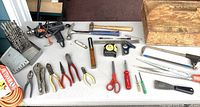 Top-down view of the entire tool kit laid out on a table, showing all the hand tools, power drill, drill bits, and wooden carrying box.