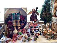 Full view of Christmas decorations lot on table including tree, nutcrackers, wreath, candles, ornaments, angel figure, and decorative houses.