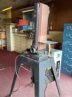 Photo showing Craftsman belt and disk sander mounted on a black metal stand with sanding belt in place and electrical cord.