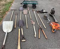 Overall lot of garden tools, electric tools and garden cart arranged on driveway