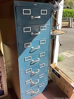 Front view of tall blue metal cabinet with seven drawers, labeled 'Cole'