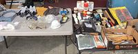 Full overview of lot displaying safety gear, gloves, respirator masks on left table; painting supplies including brushes, finishes, heat gun, scrapers on right table.