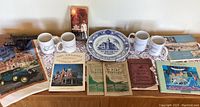 Photo showing the Port Townsend old booklets, two Puget Express mugs, commemorative plate, and KIWANIS cloth banner.