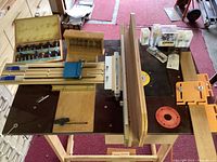 Overhead view of router table showing fence, bit sets and clamp fixtures