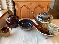 Overall view of all ceramic pieces and wooden salad tongs as a set on a table.