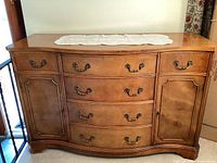 Front view of vintage wooden buffet hutch showing four central drawers and two side cabinets with brass handles.