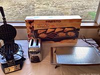 Photo showing Waring Pro waffle maker, Presto griddle box, and stainless steel toaster on surface.