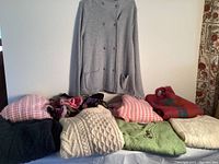 Photo showing nine different women's sweaters, various colors, styles, and knit designs, mostly wool in different textures and thicknesses.