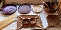 Tray with persimmons, two wooden trays, paddle-shaped wooden tray, salad bowl with utensils, brass tiered tray