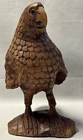 Front view of wooden carved parrot sculpture showing detailed feathers and carved base
