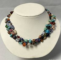 Full front view of the 3-strand multicolored beaded necklace sitting on a white display bust, showing length and colors.