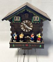 Full front view of the West German wooden cuckoo clock showing chalet style, clock face with Roman numerals, and four musical figurines.