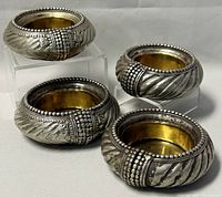 Four vintage silver plated brass bowls arranged on white background, showing exterior embossing and beaded detailing