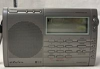 Front view of the Eton E10 shortwave radio, showing the speaker, LCD screen, multiple buttons, and tuning knobs.