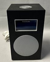 Front view of black rectangular Tivoli Audio Model 10 clock radio showing speaker grill, display window, and brand name.