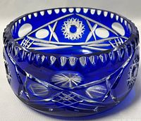 Front angled view showing scalloped rim and detailed pinwheel, geometric cuts through cobalt blue glass overlay.
