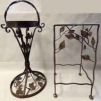 Two vintage cast metal plant stands against a plain background, one cone-shaped with leaf details and one rectangular with leaf and vine motifs.