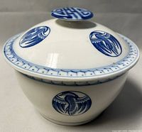 Side angle photo of the ceramic bowl with lid showing blue phoenix designs around the bowl and lid, detailing the blue Chinese character on the knob and decorative border.