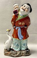 Front and side views of the vintage Jingdezhen porcelain figurine showing the woman, child, and goose details.