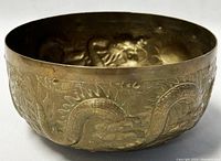 Side view of vintage brass bowl showing the embossed dragon design wrapping around the exterior surface.