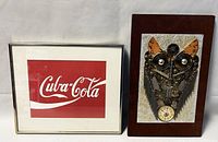 Framed Cuba-Cola wall print in silver frame with red and white logo, showing front view