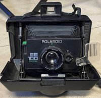 Front view of the open folding bellows camera showing lens and Polaroid EE 100 Special branding
