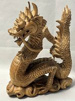 Front left side view of the hand-carved wooden dragon showing detailed facial features and body scales.