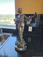 Front view of the bronze female figure statue showing detailed dress and pose.