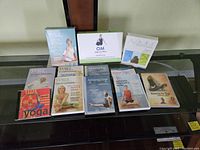 Photo showing ten yoga-themed DVDs and one box set arranged on a glass table