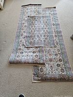 Three rugs laid on carpeted floor. Two long runners and one smaller mat on top of them. Showcasing overall size, pattern, and color.