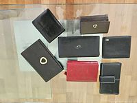 Top view showing all seven wallets of various colors and sizes placed on a glass surface.