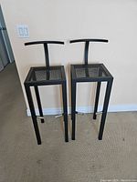 Pair of black metal bar stools showing full front and top view