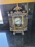 Front view of entire clock showing enamel decoration and urn finial