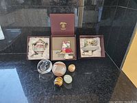 Photo showing all items including 3 boxed porcelain night lights, 1 glass squirrel paperweight and 4 onyx decorative eggs on black reflective surface